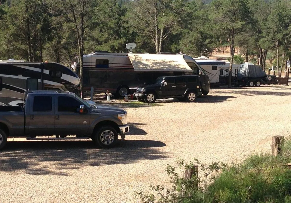 Rigs and trucks parked on a gravel terrace among the pines